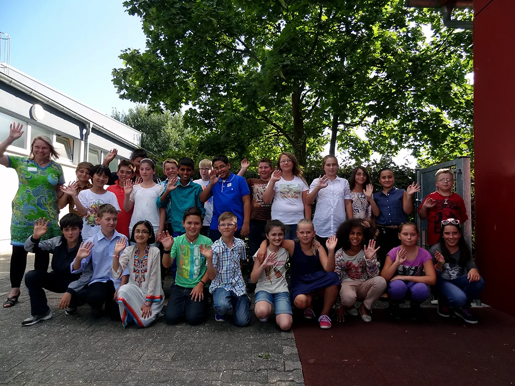 Klassenfoto einer neuen fünften Klasse auf dem Schulhof unter Bäumen.